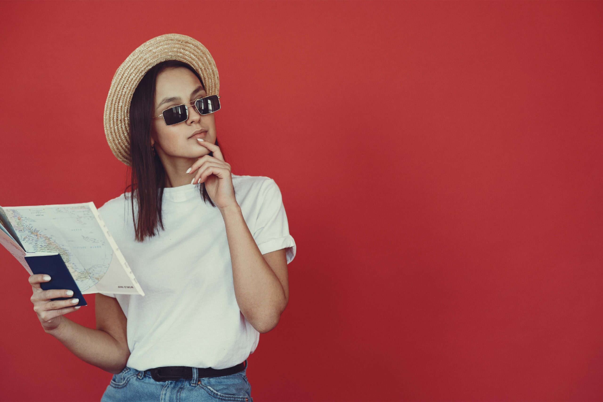 Pensive young female hipster with map on red background