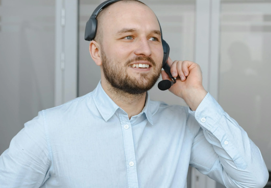 Smiling Man in Blue Long Sleeves Wearing a Black Headset