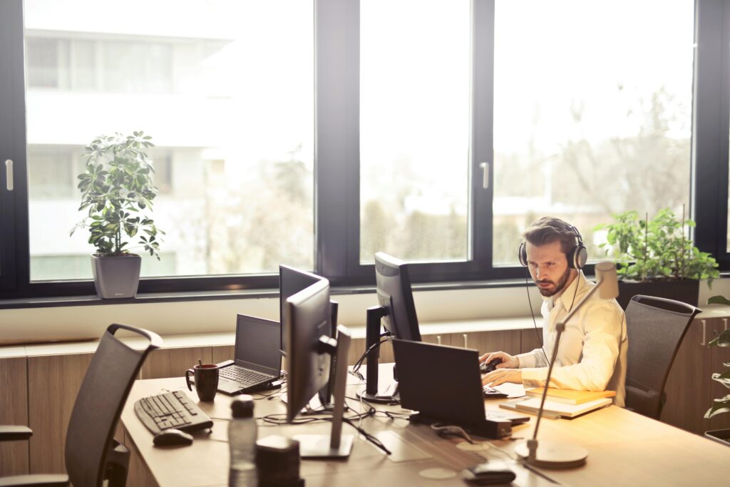 Man With Headphones Facing Computer Monitor
